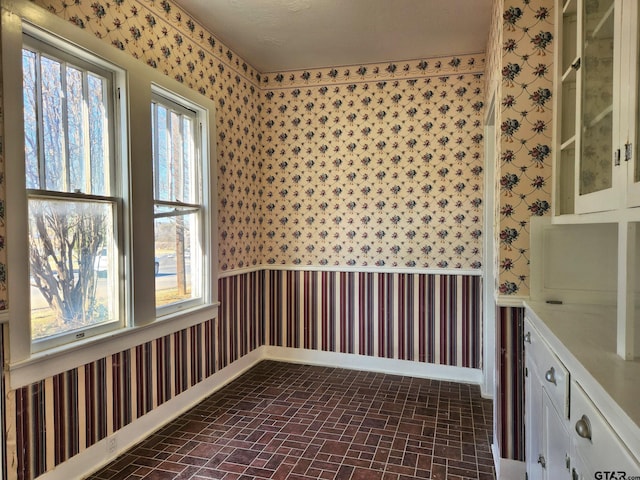 501 E Park Ave, Palestine, TX 75801 - spare room with wallpapered walls, brick patterned flooring, and baseboards