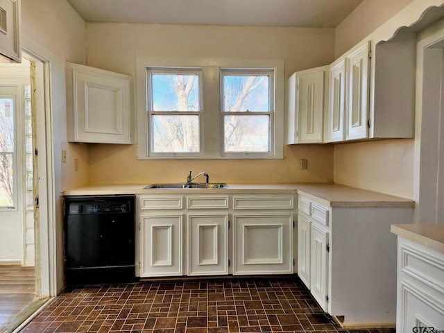 501 E Park Ave, Palestine, TX 75801 - kitchen with black dishwasher, a sink, light countertops, and brick patterned floors