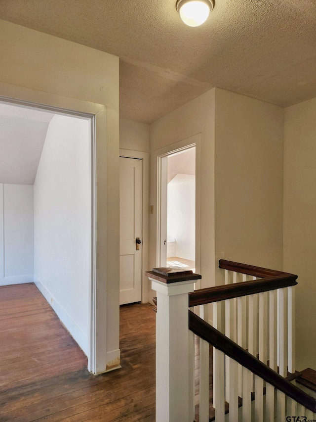 hall with a textured ceiling and dark hardwood / wood-style flooring