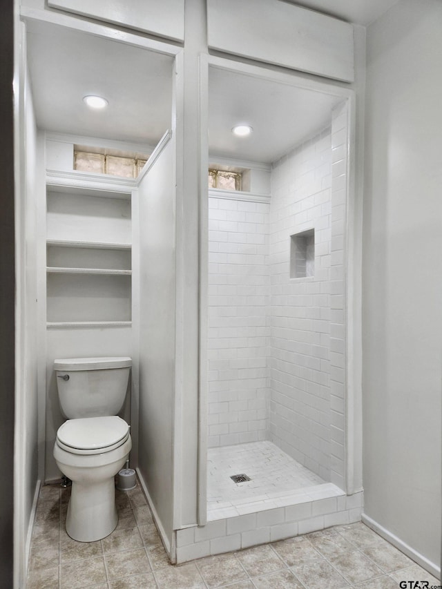 bathroom with toilet, tile patterned floors, and tiled shower