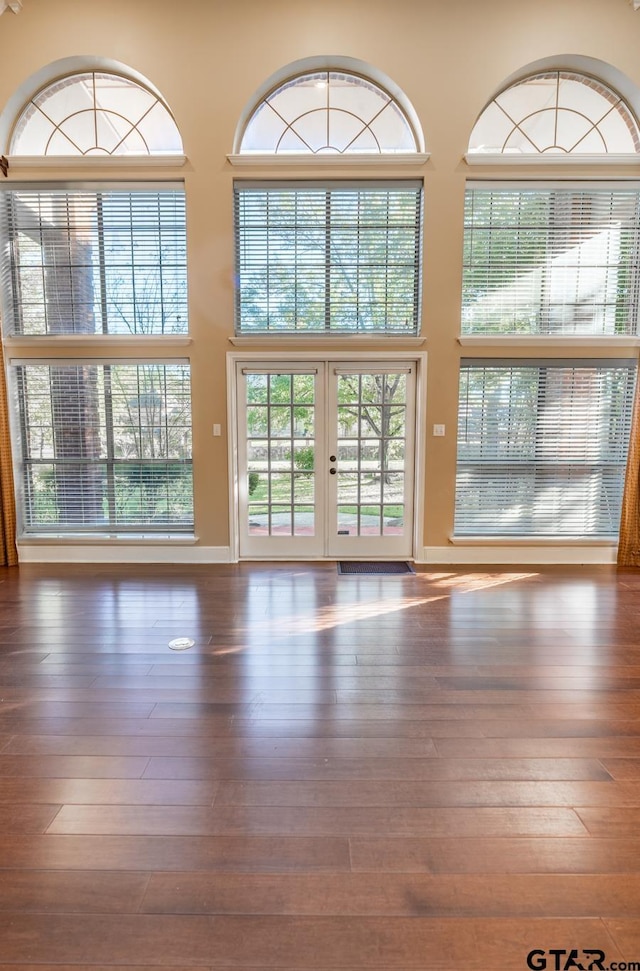 unfurnished living room featuring french doors, dark hardwood / wood-style flooring, and a high ceiling