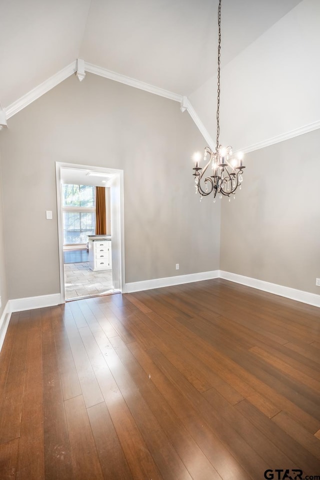 unfurnished room featuring hardwood / wood-style floors, ornamental molding, lofted ceiling, and an inviting chandelier