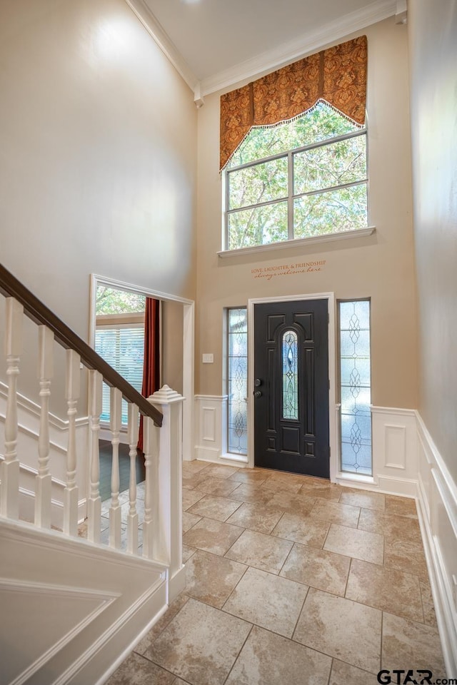 entrance foyer featuring a healthy amount of sunlight, crown molding, and a high ceiling