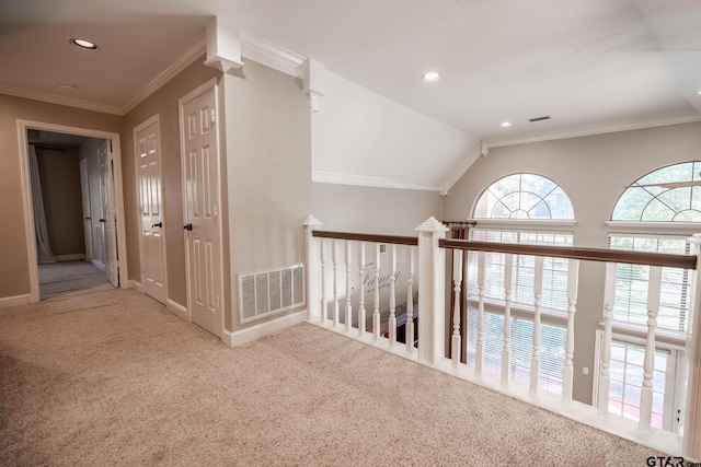 hall with light colored carpet, ornamental molding, and vaulted ceiling