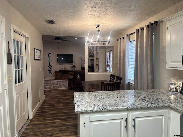 kitchen featuring decorative light fixtures, light stone countertops, a textured ceiling, and white cabinets