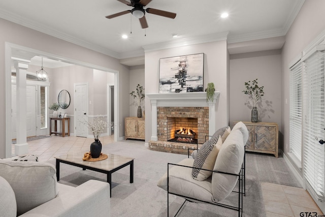 living room with light carpet, ornate columns, ceiling fan with notable chandelier, crown molding, and a fireplace