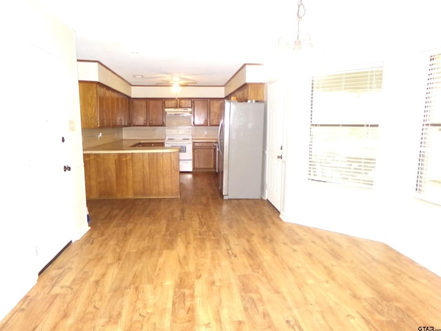 803 Corey, Whitehouse, TX 75791 - kitchen with white electric range, freestanding refrigerator, brown cabinets, a peninsula, and light countertops