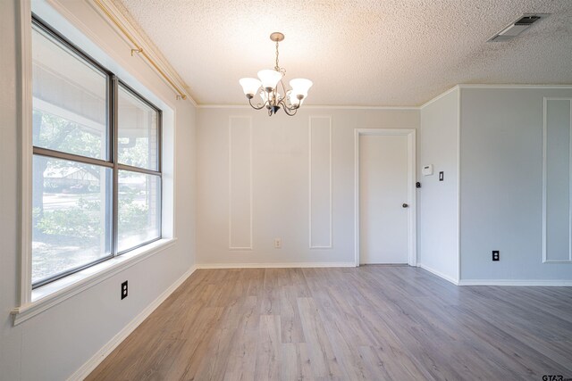 spare room featuring hardwood / wood-style flooring, ornamental molding, a textured ceiling, and a notable chandelier