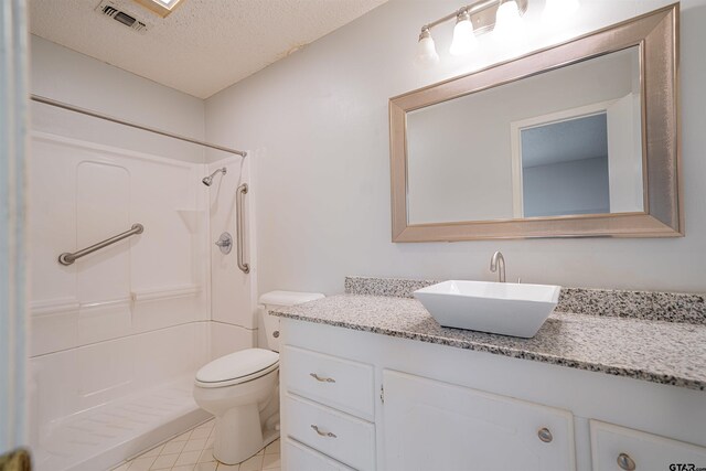 bathroom featuring walk in shower, vanity, a textured ceiling, and toilet