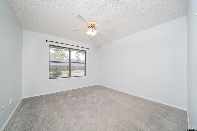 empty room featuring ceiling fan, a textured ceiling, and light colored carpet