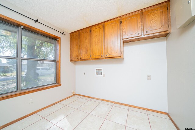 clothes washing area with cabinets, light tile patterned flooring, washer hookup, a textured ceiling, and hookup for an electric dryer