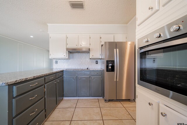 kitchen with white cabinets, light tile patterned floors, tasteful backsplash, ornamental molding, and appliances with stainless steel finishes