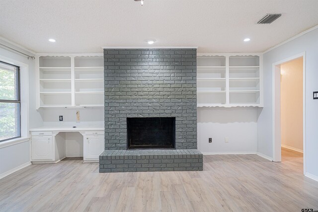 unfurnished living room featuring a fireplace, light hardwood / wood-style floors, a textured ceiling, and crown molding