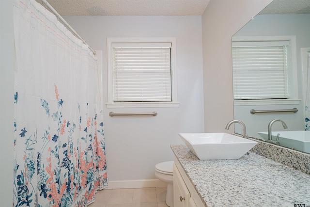 bathroom with toilet, vanity, a wealth of natural light, and tile patterned flooring