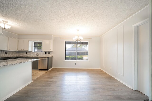 kitchen with stainless steel dishwasher, a wealth of natural light, white cabinetry, and light hardwood / wood-style floors