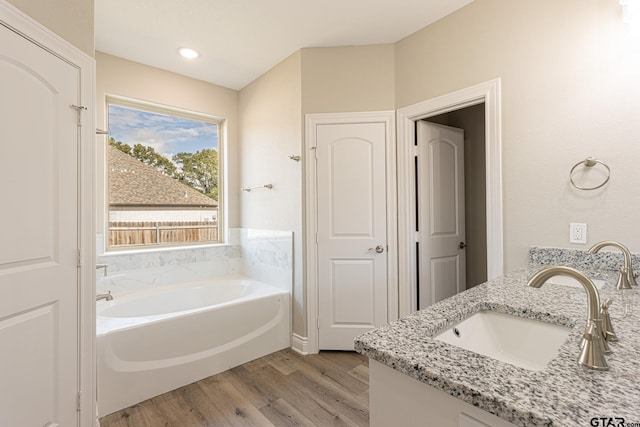 bathroom featuring wood-type flooring, vanity, and a bathing tub