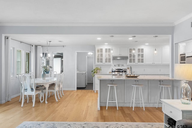 21028 Bay Shore Dr, Flint, TX 75762 - kitchen featuring under cabinet range hood, stainless steel range, a chandelier, light wood finished floors, and white cabinetry