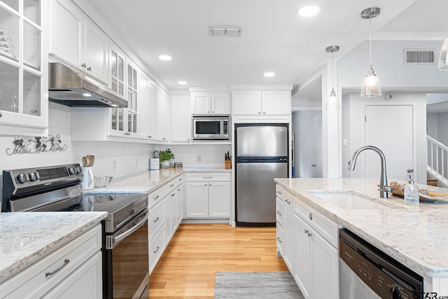 21028 Bay Shore Dr, Flint, TX 75762 - kitchen featuring appliances with stainless steel finishes, under cabinet range hood, white cabinets, light wood finished floors, and recessed lighting