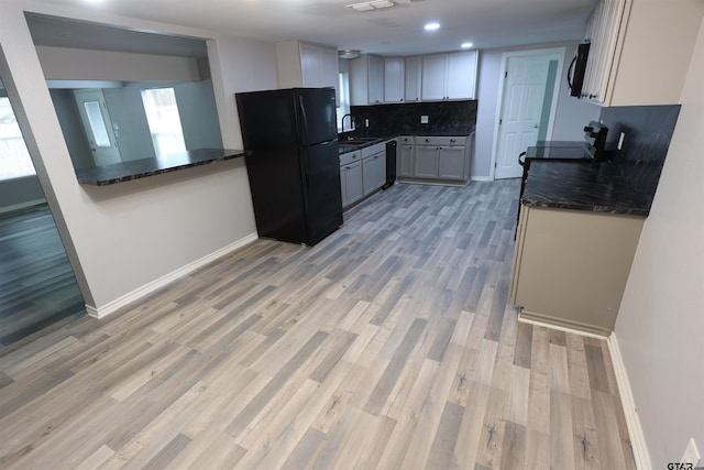 199 Linda Dr, Jefferson, TX 75657 - kitchen with black appliances, a sink, baseboards, tasteful backsplash, and light wood-style floors