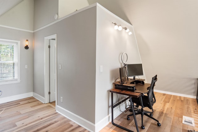 home office with light hardwood / wood-style floors and lofted ceiling