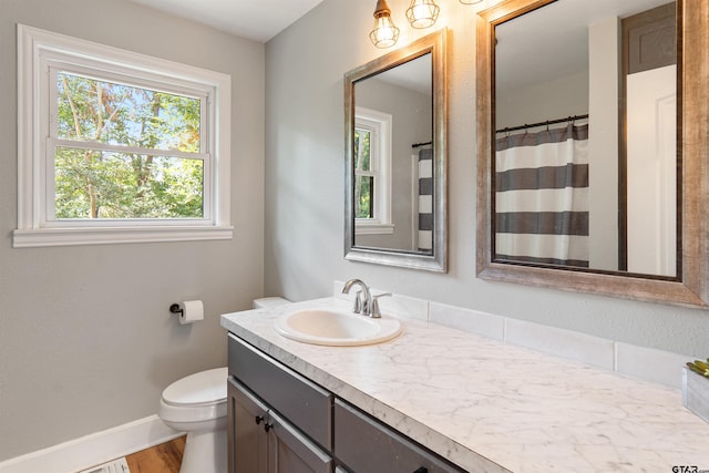 bathroom featuring toilet, vanity, hardwood / wood-style floors, and a healthy amount of sunlight