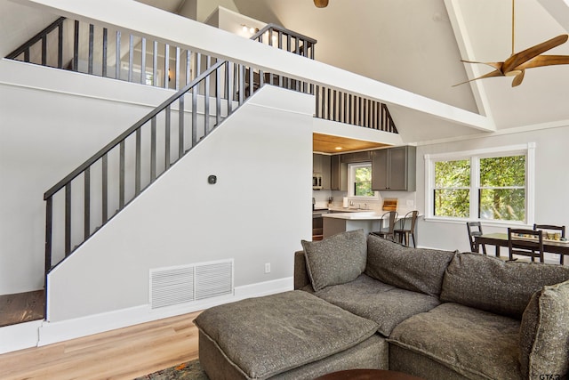 living room featuring beamed ceiling, hardwood / wood-style flooring, ceiling fan, and high vaulted ceiling