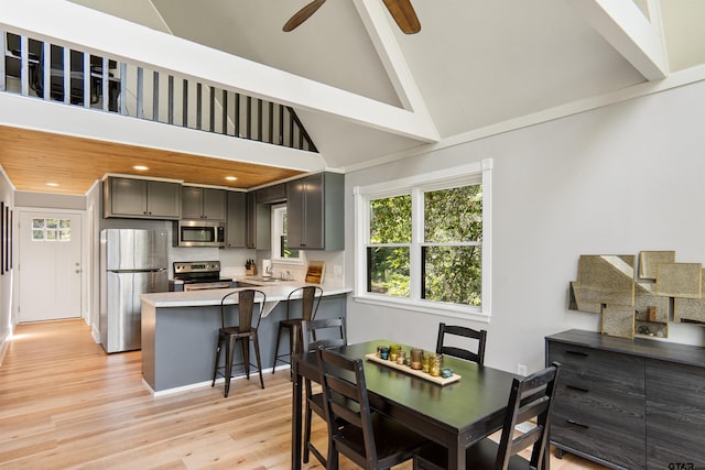 dining space with light wood-type flooring, ceiling fan, and high vaulted ceiling