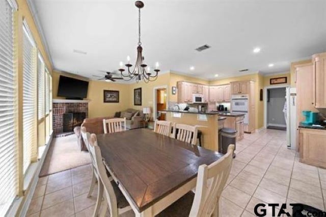 tiled dining room featuring a fireplace and ceiling fan with notable chandelier