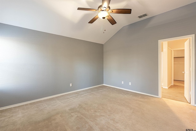 spare room with light colored carpet, vaulted ceiling, and ceiling fan