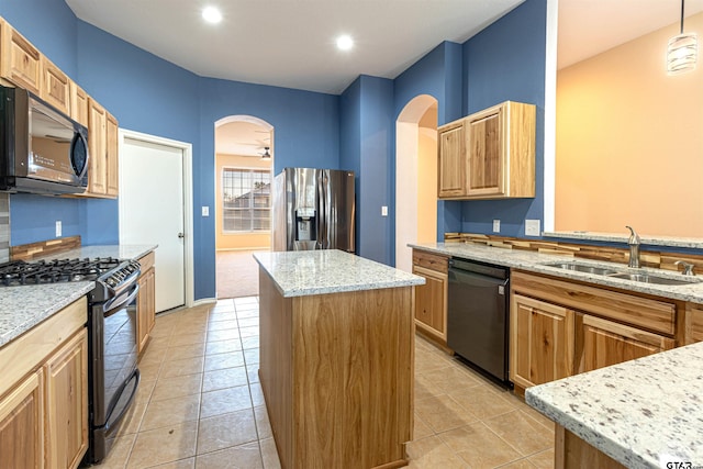 kitchen with black appliances, a center island, sink, decorative light fixtures, and light stone counters