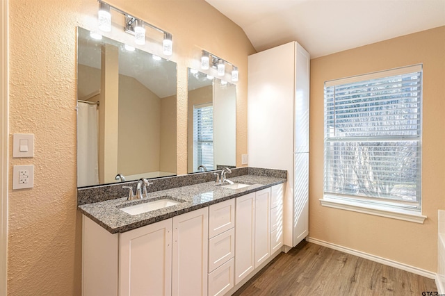 bathroom with wood-type flooring, plenty of natural light, vaulted ceiling, and vanity