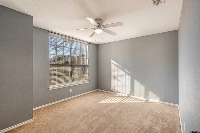 empty room with ceiling fan, a textured ceiling, and light carpet