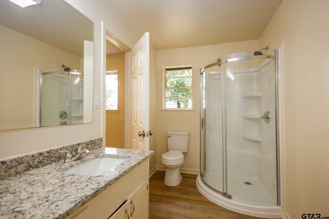 bathroom with hardwood / wood-style flooring, vanity, toilet, and a shower with shower door