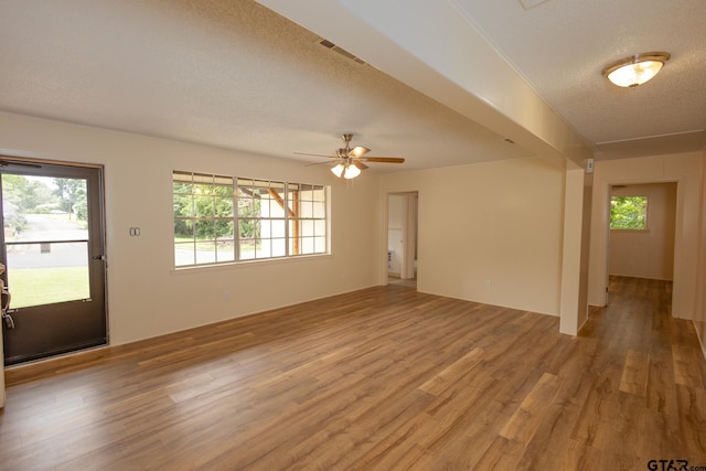 unfurnished living room with a textured ceiling, hardwood / wood-style flooring, and ceiling fan