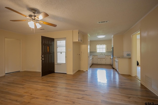 kitchen with sink, ceiling fan, light wood-type flooring, a textured ceiling, and white cabinetry