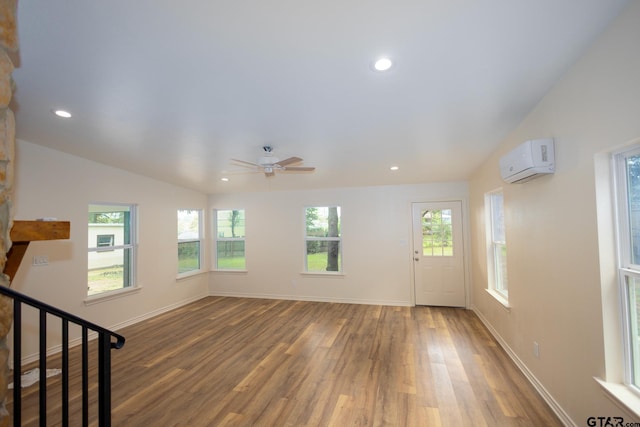 unfurnished living room with hardwood / wood-style flooring, ceiling fan, lofted ceiling, and a wall unit AC