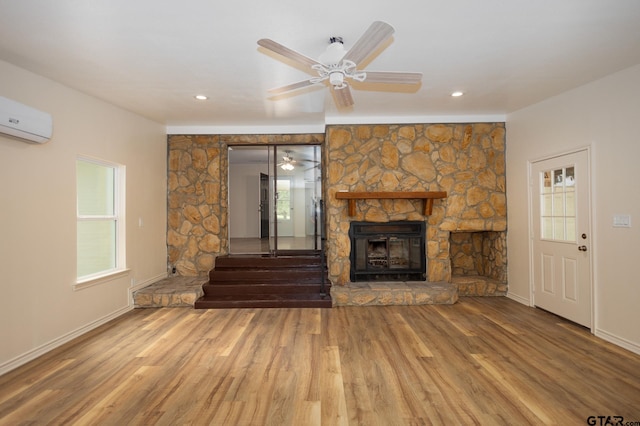 unfurnished living room featuring hardwood / wood-style floors, ceiling fan, a fireplace, and a wall mounted AC