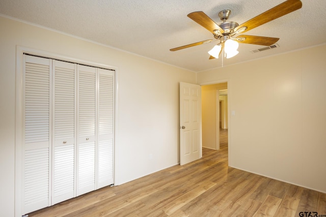 unfurnished bedroom featuring ceiling fan, a closet, a textured ceiling, and light wood-type flooring