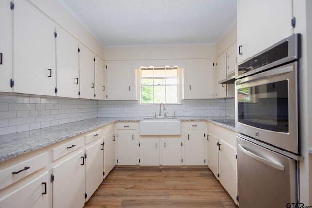 kitchen featuring decorative backsplash, white cabinetry, and sink