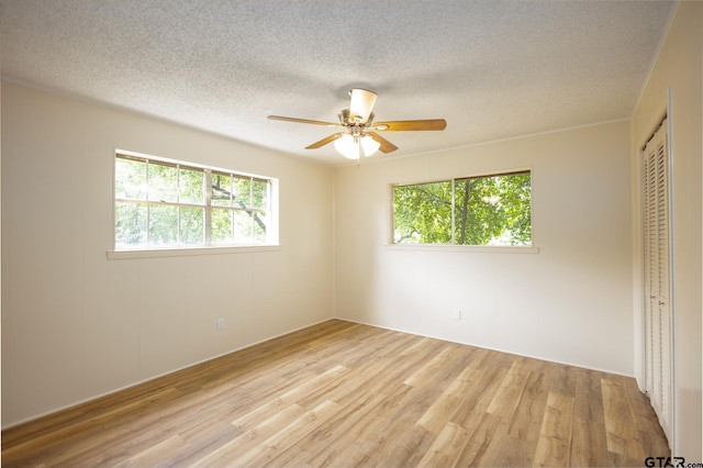 unfurnished bedroom with ceiling fan, a closet, a textured ceiling, and light hardwood / wood-style flooring