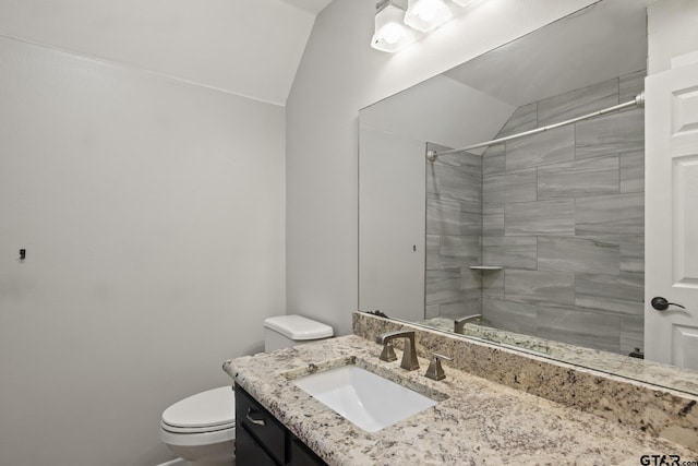 bathroom with toilet, tiled shower, and vaulted ceiling