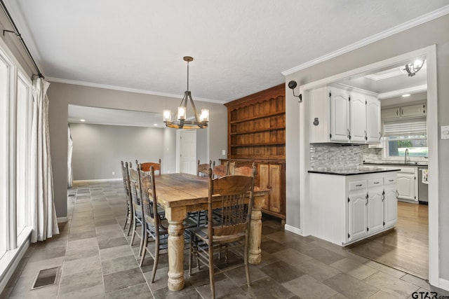 dining space featuring sink, a chandelier, and ornamental molding