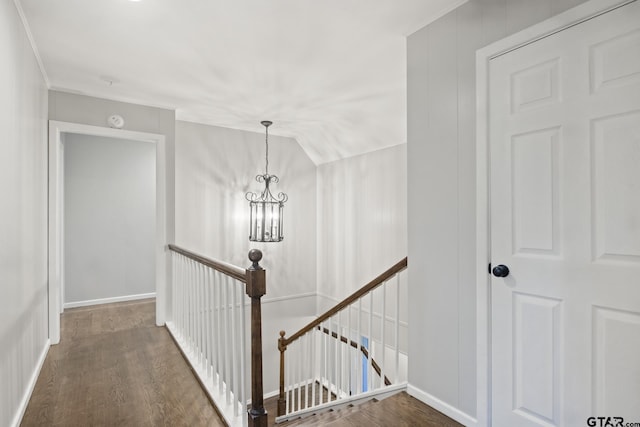 hallway with a notable chandelier, dark hardwood / wood-style floors, and vaulted ceiling