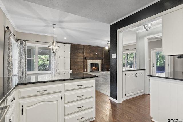 kitchen featuring white cabinetry, a large fireplace, ceiling fan, hanging light fixtures, and dark wood-type flooring