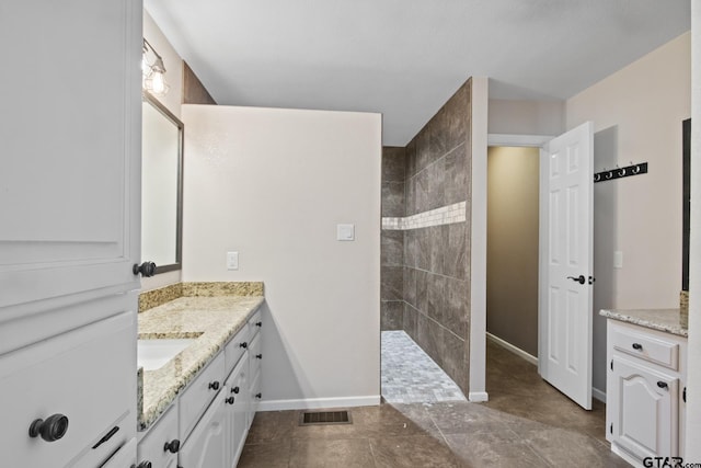 bathroom with tiled shower and vanity