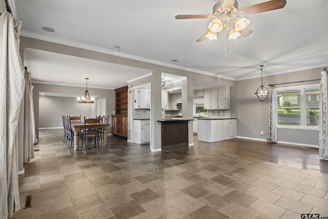 kitchen with a center island, backsplash, white cabinets, ceiling fan with notable chandelier, and ornamental molding