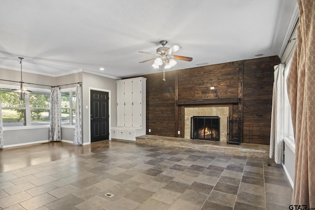 unfurnished living room featuring ceiling fan with notable chandelier, wood walls, and crown molding