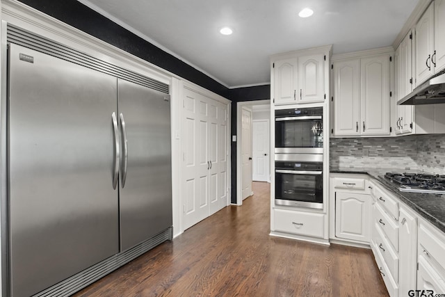 kitchen with white cabinets, decorative backsplash, dark wood-type flooring, and appliances with stainless steel finishes