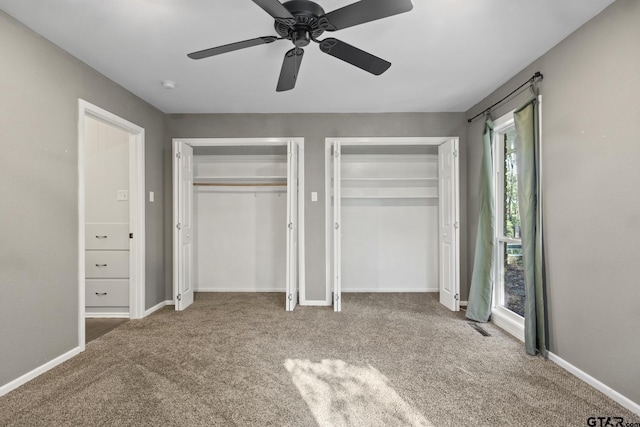 unfurnished bedroom with multiple closets, ceiling fan, and carpet