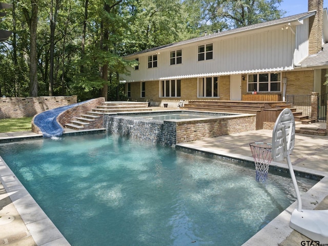 view of swimming pool featuring an in ground hot tub and a water slide